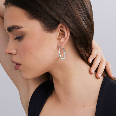 woman wearing oval-shaped sterling silver beaded hoop earrings