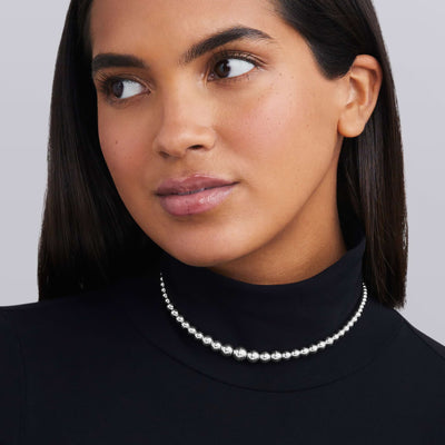 woman wearing sterling silver thin to thick beaded necklace
